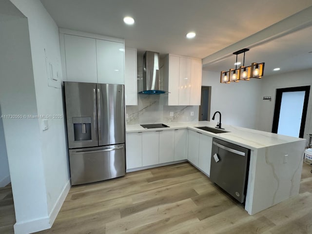 kitchen featuring white cabinetry, appliances with stainless steel finishes, kitchen peninsula, pendant lighting, and wall chimney range hood