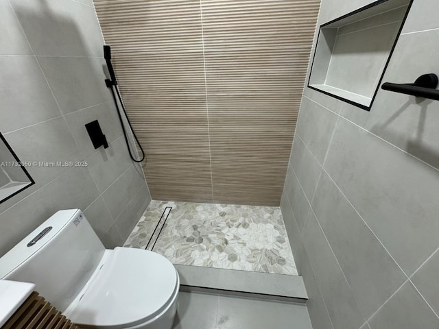 bathroom featuring tiled shower, tile walls, and toilet