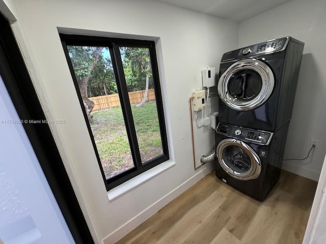 laundry area with light hardwood / wood-style floors and stacked washer / dryer