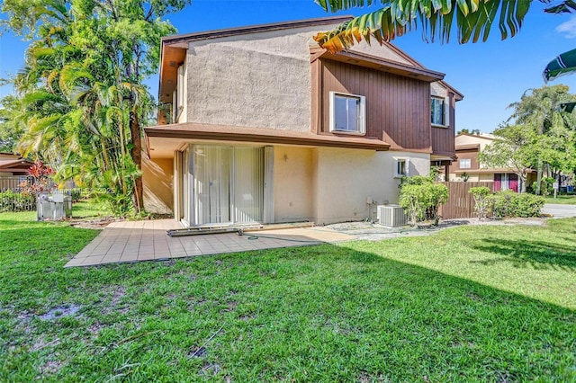 rear view of property featuring cooling unit, a yard, and a patio area