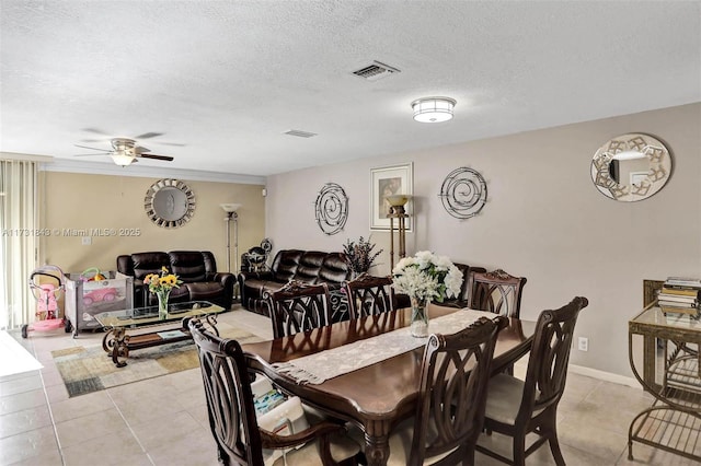 tiled dining room with ceiling fan and a textured ceiling