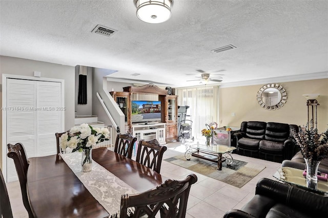 dining area featuring light tile patterned floors, ornamental molding, a textured ceiling, and ceiling fan