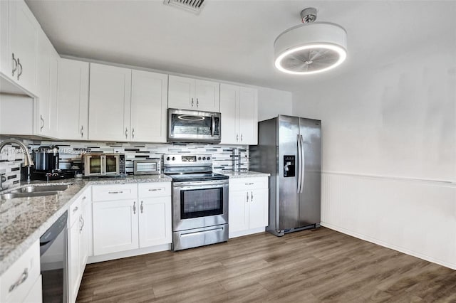 kitchen with sink, white cabinets, backsplash, stainless steel appliances, and light stone countertops