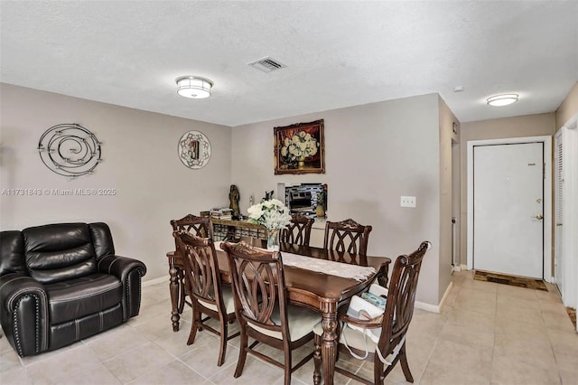 dining area featuring light tile patterned floors and a textured ceiling