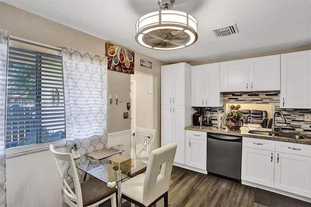 kitchen featuring dishwasher, sink, white cabinets, backsplash, and dark stone counters