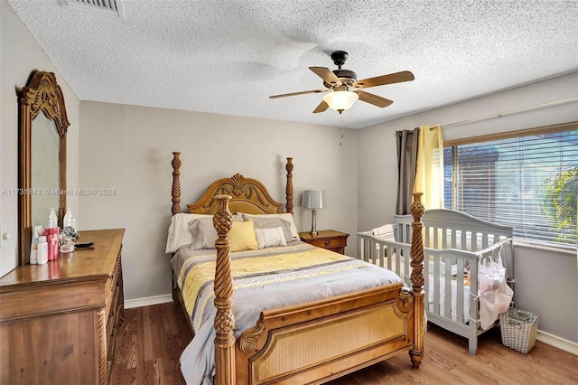 bedroom featuring ceiling fan, hardwood / wood-style floors, and a textured ceiling