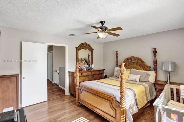 bedroom with a textured ceiling, light hardwood / wood-style flooring, and ceiling fan