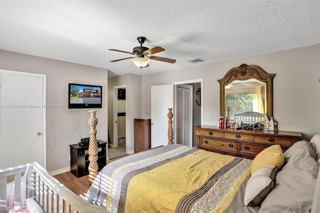 bedroom featuring light wood-type flooring, a textured ceiling, ceiling fan, and a closet