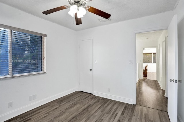 spare room featuring dark wood-type flooring, ceiling fan, and a textured ceiling