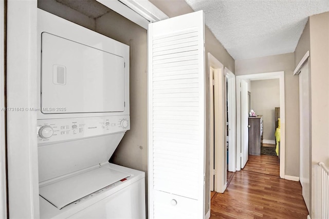 laundry room with hardwood / wood-style floors, radiator heating unit, a textured ceiling, and stacked washer / dryer