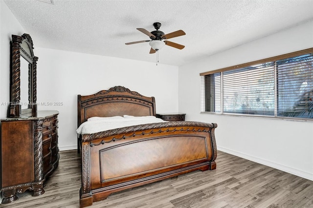 bedroom with a textured ceiling, wood-type flooring, and ceiling fan