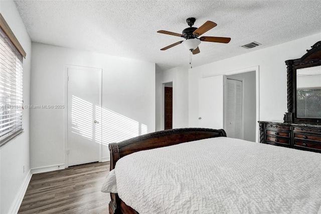 bedroom with a textured ceiling, wood-type flooring, a closet, and ceiling fan