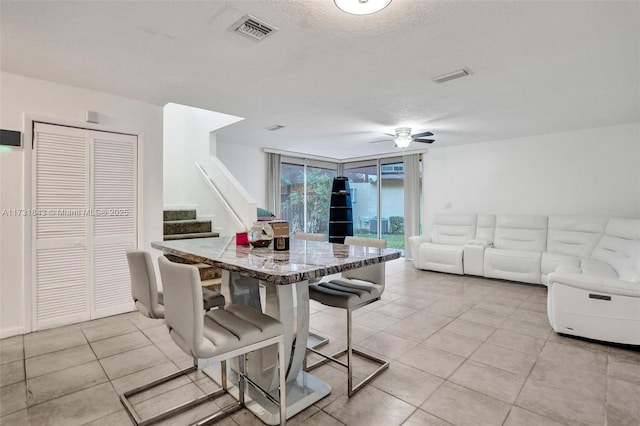 tiled dining area featuring ceiling fan, floor to ceiling windows, and a textured ceiling