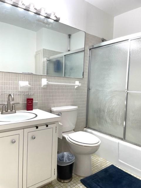 full bathroom featuring vanity, shower / bath combination with glass door, and toilet