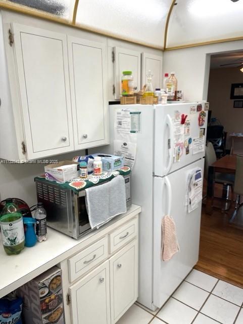 kitchen featuring white refrigerator, white cabinetry, and light tile patterned floors