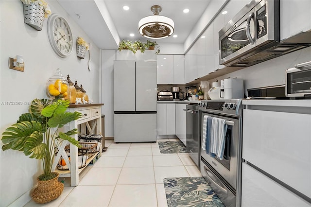 kitchen featuring stainless steel appliances, light tile patterned floors, and white cabinets