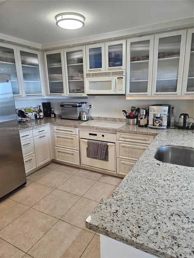 kitchen featuring white appliances, light stone countertops, sink, and light tile patterned floors