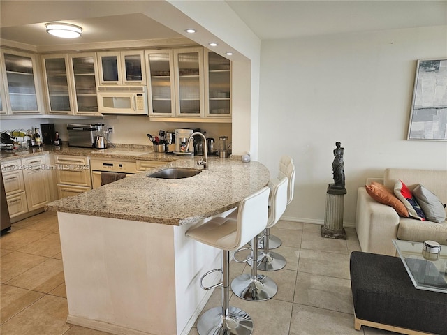 kitchen with sink, white appliances, light stone countertops, and light tile patterned floors