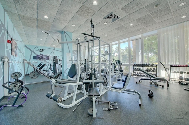 workout area with floor to ceiling windows and a drop ceiling