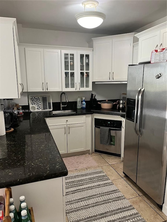 kitchen featuring sink, light tile patterned floors, white cabinetry, dark stone countertops, and stainless steel appliances