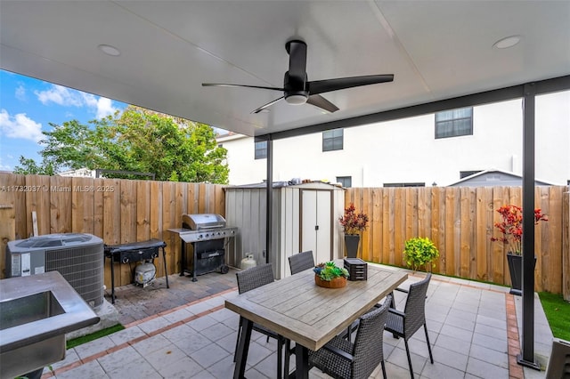 view of patio featuring cooling unit, ceiling fan, grilling area, and a shed