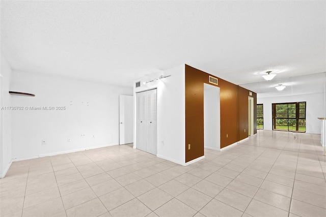 spare room with a textured ceiling and light tile patterned floors