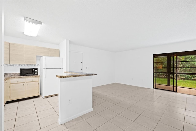 kitchen with white refrigerator, a textured ceiling, light stone counters, and light tile patterned floors