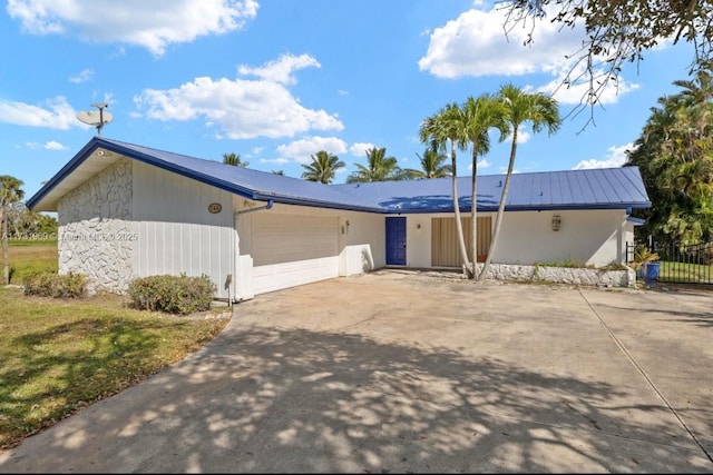 view of front of property with an attached garage, metal roof, and concrete driveway