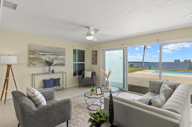 living room featuring light tile patterned floors, visible vents, a city view, and a wealth of natural light