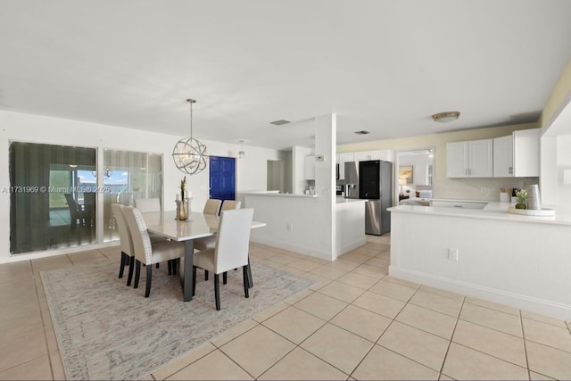 dining space featuring light tile patterned floors, baseboards, and a notable chandelier