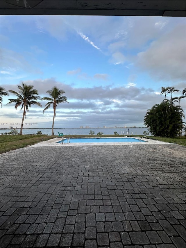 view of pool featuring a water view and a patio area