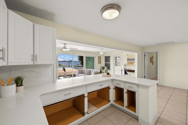 kitchen with light tile patterned floors, a peninsula, light countertops, and white cabinets