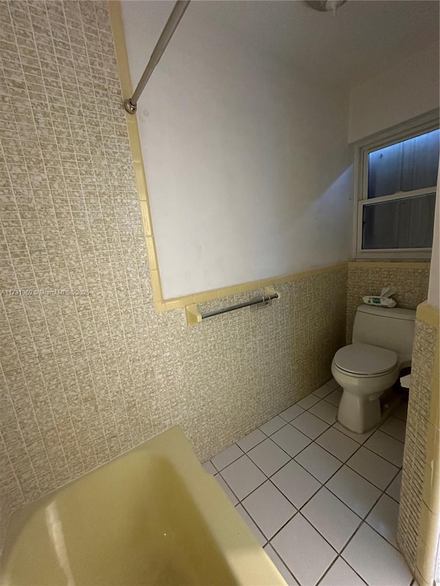 bathroom featuring tile walls, a bathtub, tile patterned flooring, and toilet