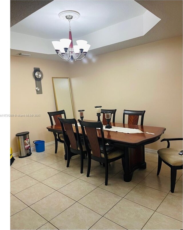 dining area featuring a raised ceiling, light tile patterned flooring, and a chandelier