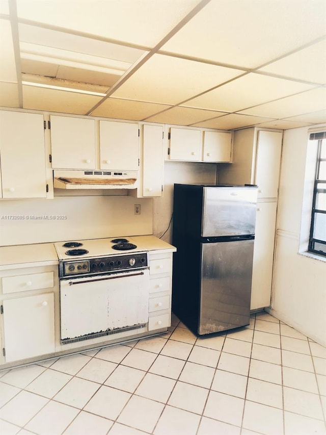 kitchen featuring light tile patterned flooring, white electric range oven, a drop ceiling, stainless steel refrigerator, and white cabinets