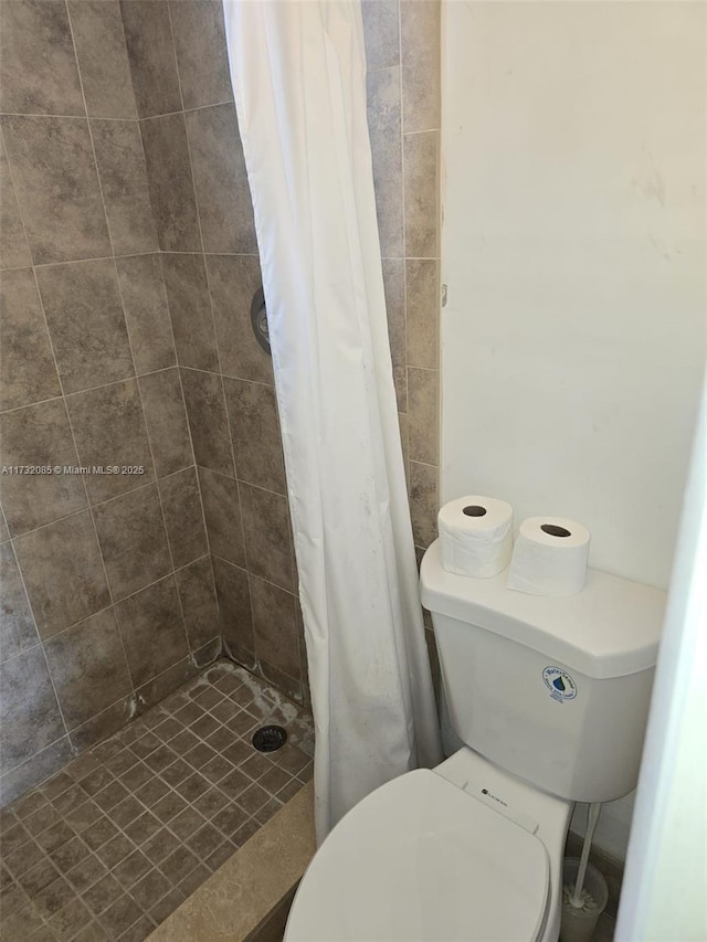 bathroom featuring toilet and curtained shower