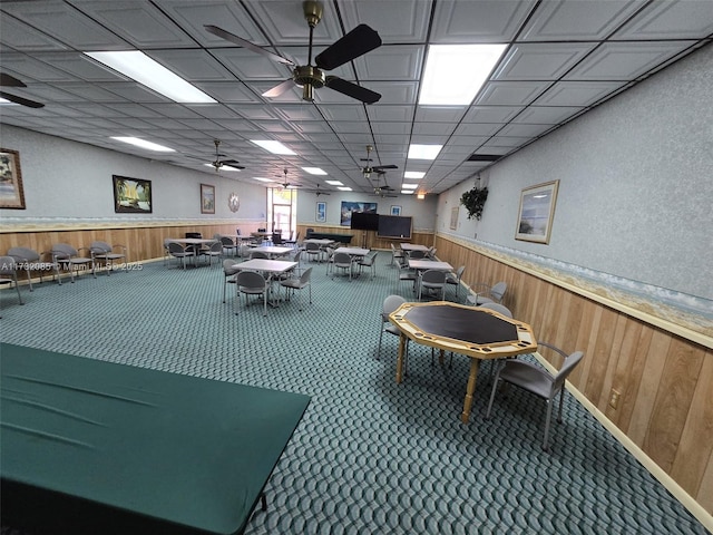 misc room with ceiling fan, wooden walls, and carpet