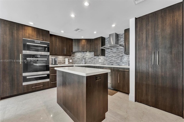 kitchen featuring a kitchen island, tasteful backsplash, sink, dark brown cabinetry, and wall chimney range hood