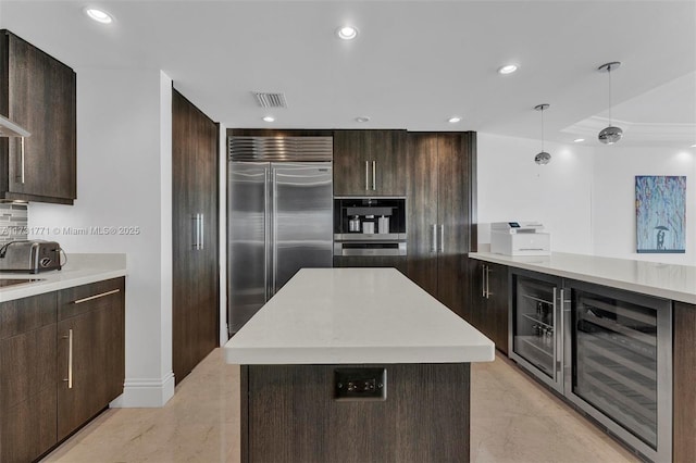 kitchen featuring a kitchen island, decorative light fixtures, tasteful backsplash, wine cooler, and stainless steel appliances