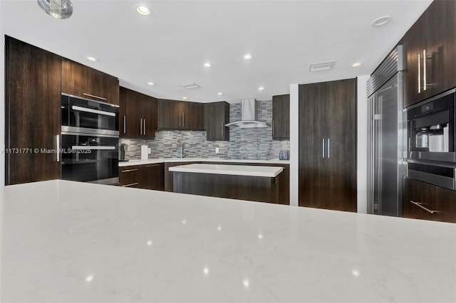 kitchen with tasteful backsplash, dark brown cabinets, black electric cooktop, and wall chimney exhaust hood