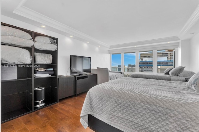 bedroom with ornamental molding, dark hardwood / wood-style flooring, and a tray ceiling