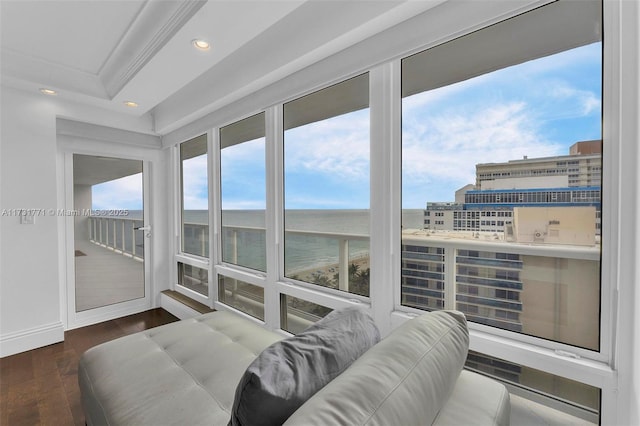 sunroom featuring a water view and a tray ceiling