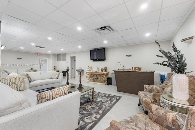 living room with sink, light tile patterned floors, and a paneled ceiling