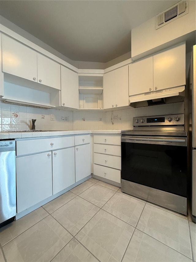 kitchen with stainless steel appliances, white cabinetry, tasteful backsplash, and light tile patterned floors