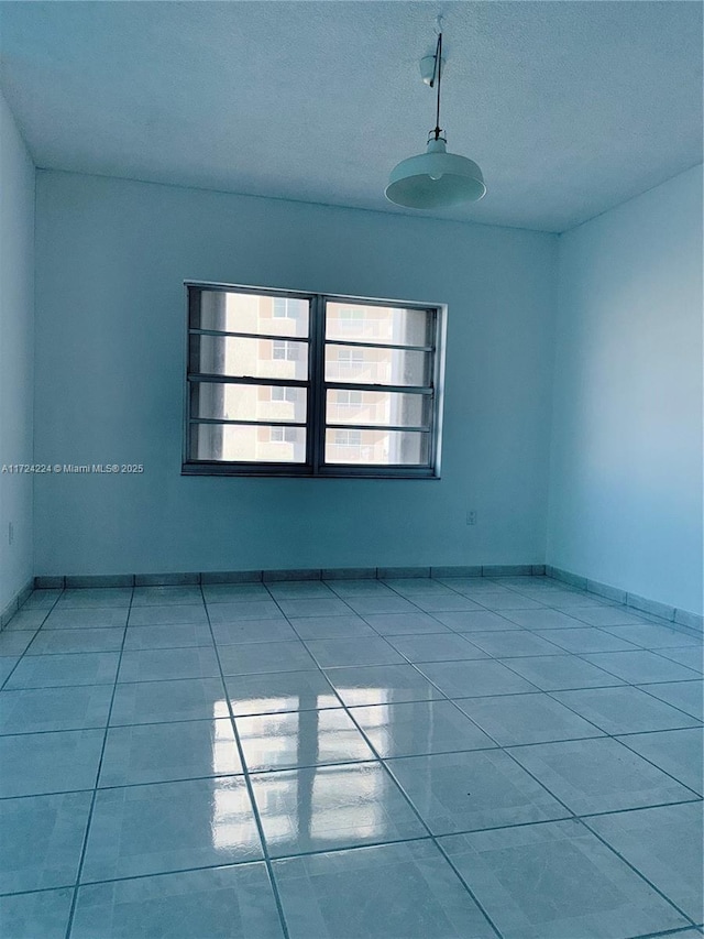 spare room featuring light tile patterned floors and a textured ceiling