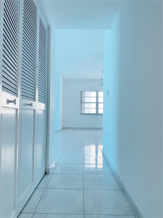 corridor with a textured ceiling and light tile patterned floors