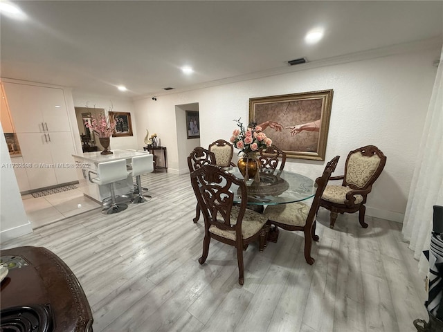 dining room with ornamental molding and light hardwood / wood-style flooring