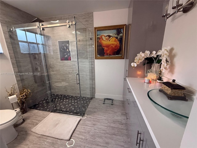 bathroom featuring vanity, a shower with shower door, and toilet