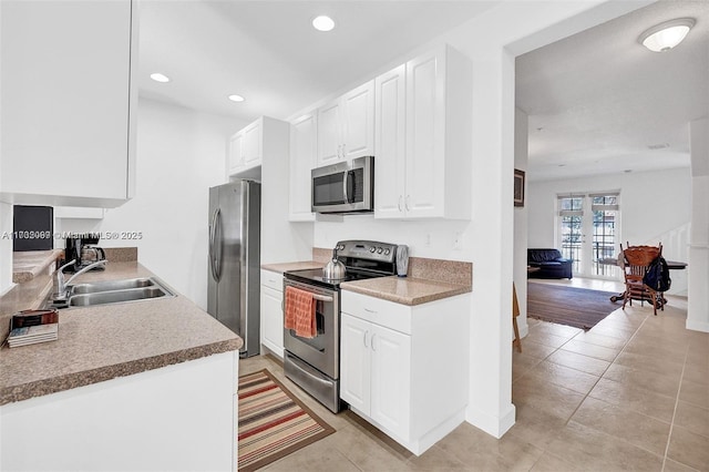 kitchen with white cabinetry, appliances with stainless steel finishes, sink, and light tile patterned floors