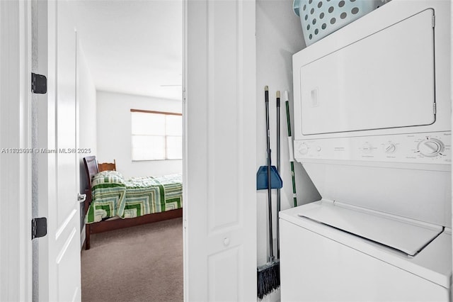 clothes washing area featuring stacked washer / drying machine and carpet floors